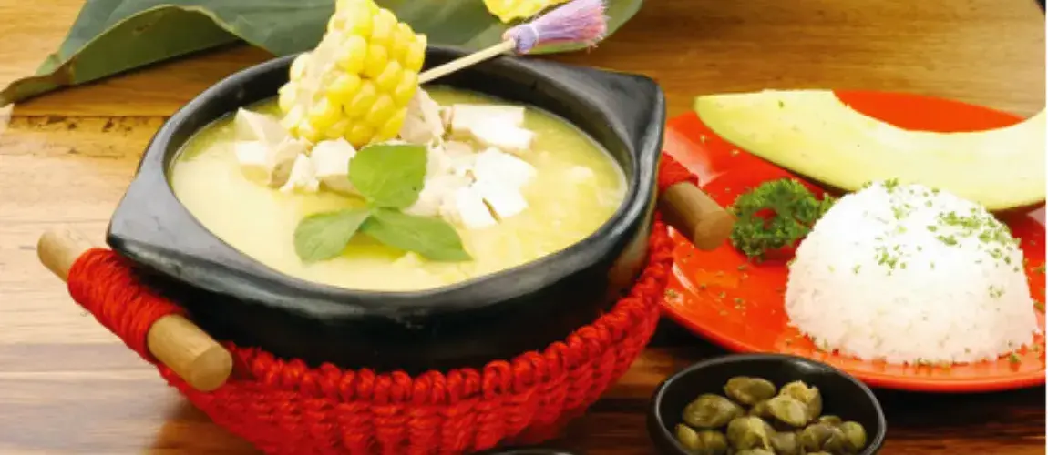 Ajiaco (sopa de pollo y papa) con una rodaja de mazorca de maíz y queso, servido en un recipiente