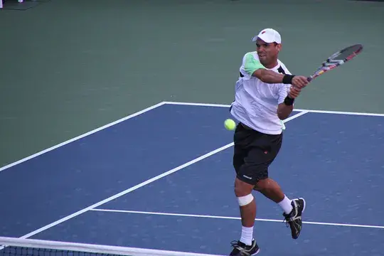 Tenista colombiano, Alejandro Falla, golpeando la pelota de revés en una cancha azul al aire libre.