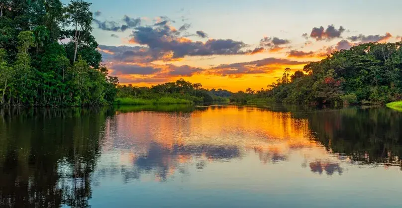 Sunset reflected on Amazon river surrounded by jungle