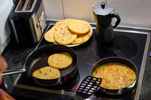 Arepas browning in the pan with homemade pericos.