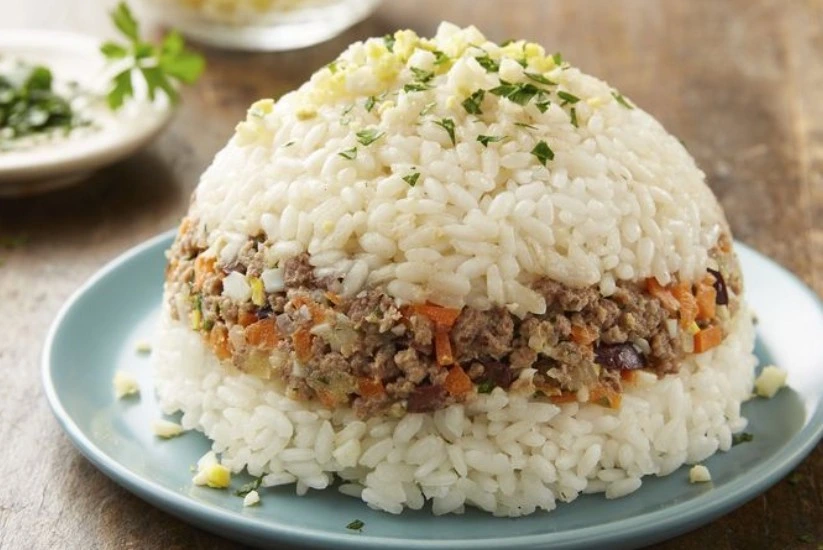 Arroz tapado con carne molida, zanahoria y otros vegetales, servido en un plato azul