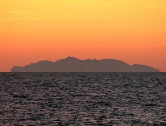 Gorgona Island at sunset with bright orange sky