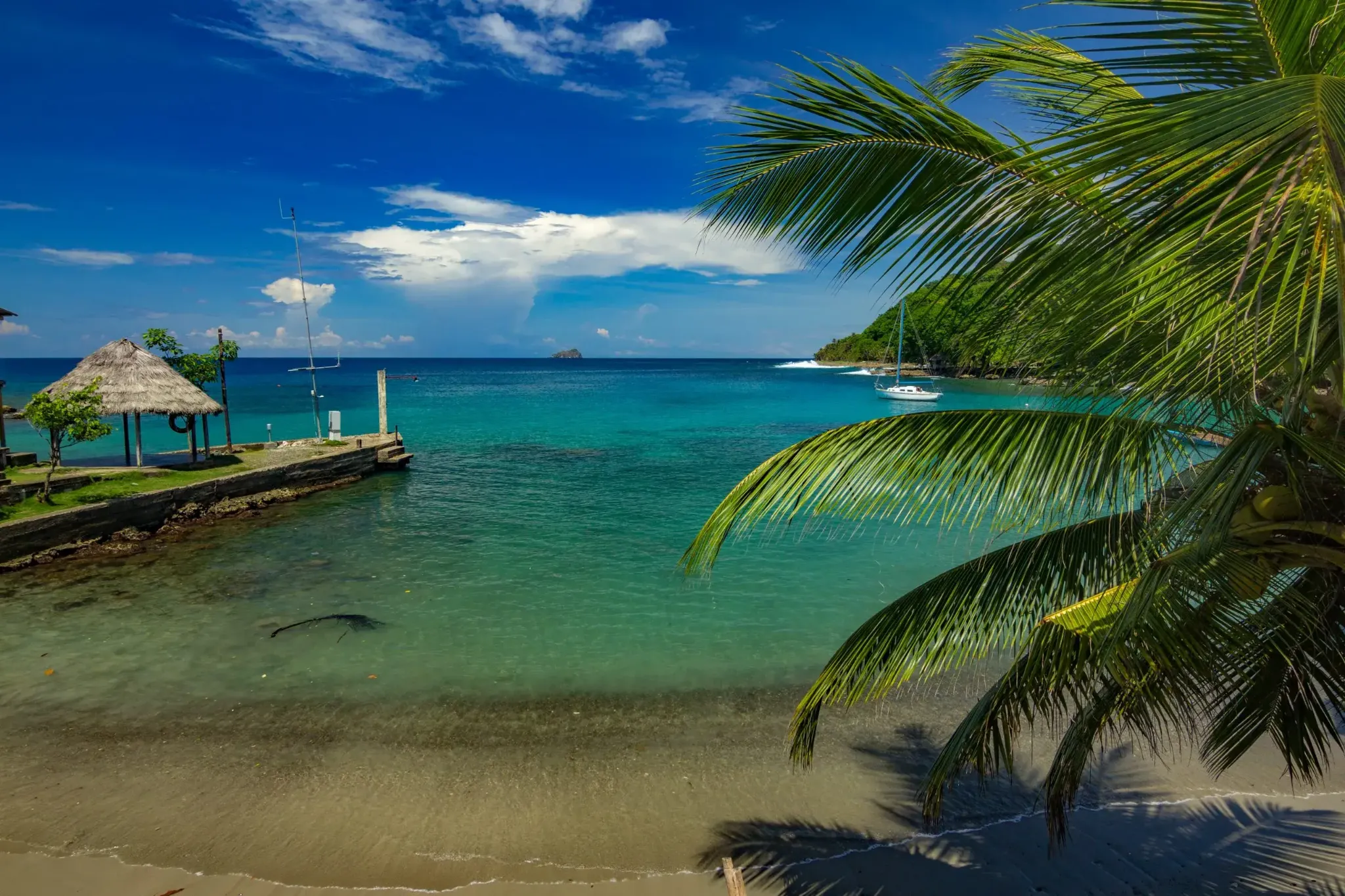 Bahía de aguas cristalinas con palmeras y velero en Colombia