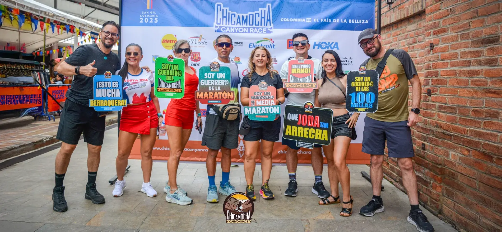 Grupo de personas posando con carteles coloridos en la Chicamocha Canyon Race 2025 en San Gil, Colombia