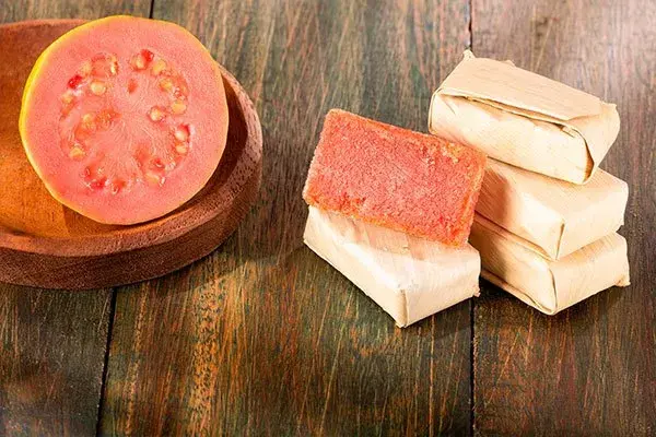 Bocadillo de guayaba con fruta fresca sobre mesa de madera.