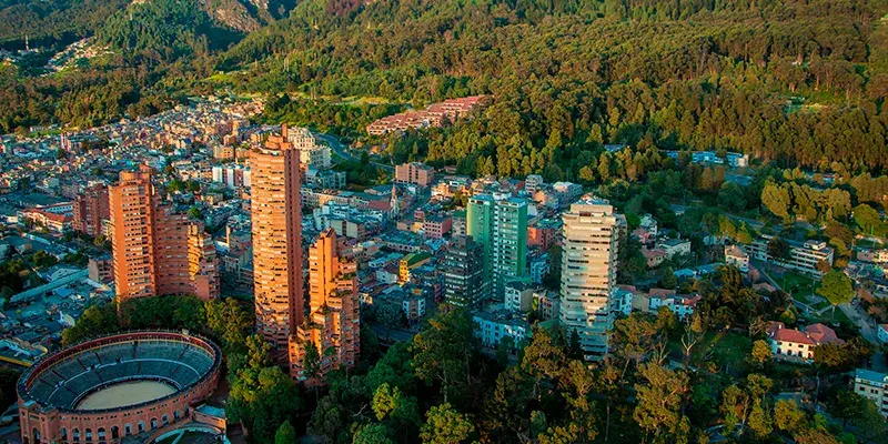 Aerial view of Bogota with high-rise buildings and forest in the background