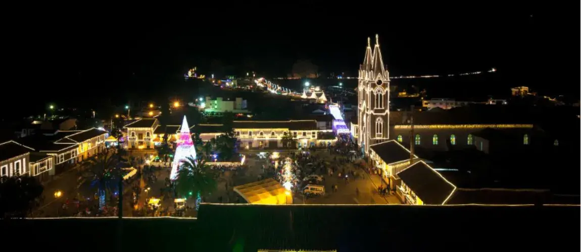Plaza nocturna con iglesia iluminada y árbol de Navidad