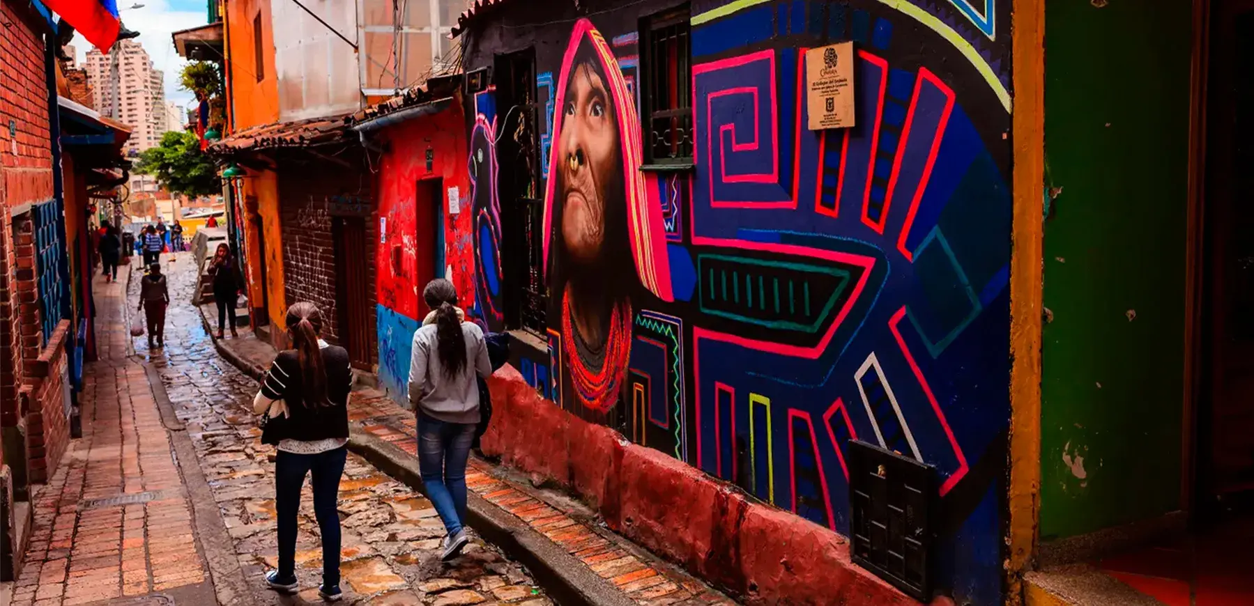 Callejón del Embudo en La Candelaria Bogotá decorado con coloridos murales y personas caminando