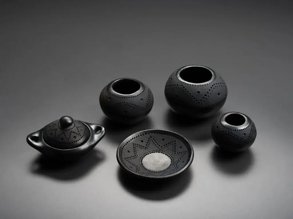 Conjunto de cinco piezas de cerámica negra con decoración de puntos.