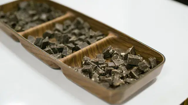 Trozos irregulares de chocolate oscuro en una bandeja de madera de tres compartimentos.