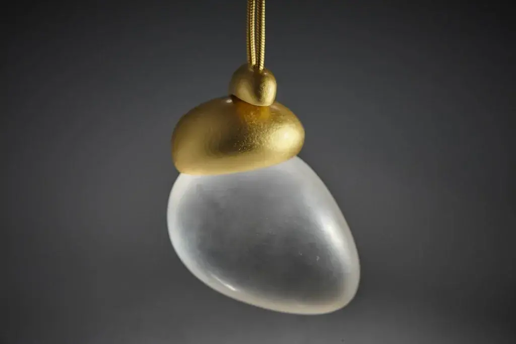 Colgante de oro y cuarzo, forma de gota, sobre fondo gris.