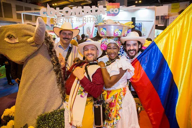 Grupo de colombianos con trajes típicos y bandera en feria.
