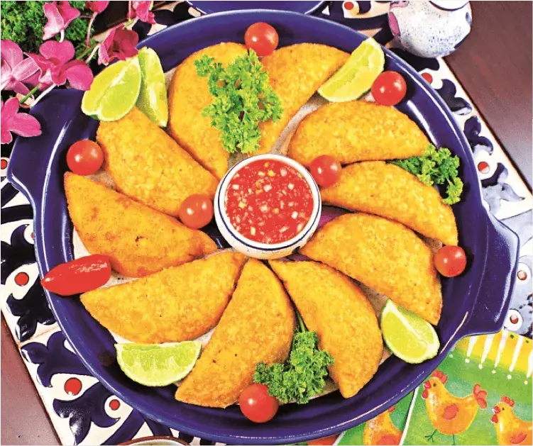 Once empanadas de pipián con limón y salsa roja en plato azul.