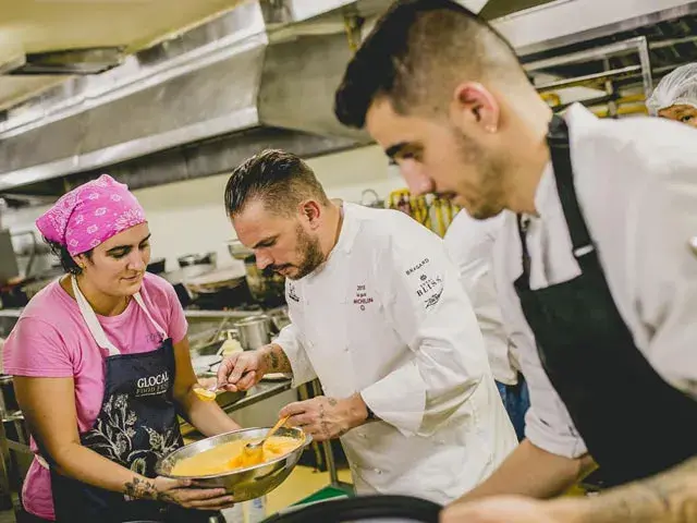 Chefs cocinando en una cocina profesional preparando una salsa amarilla.