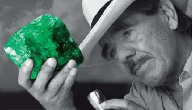Hombre con sombrero examinando una esmeralda