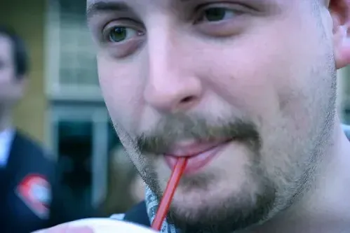 Man drinking beverage with red straw