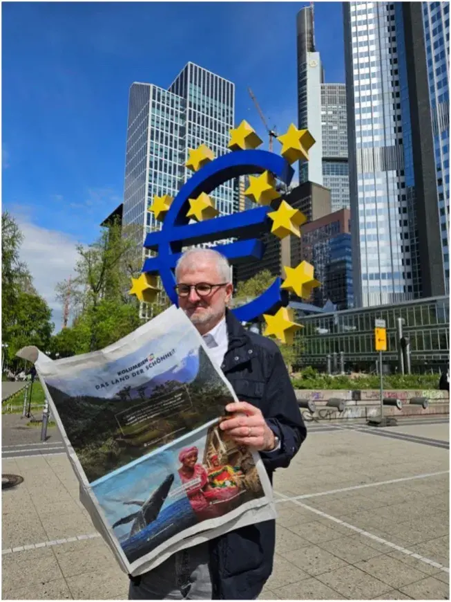 Hombre con gafas lee periódico frente a símbolo del Euro en Fráncfort.