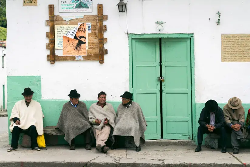 Hombres con ruana compartiendo en un pueblo colombiano.