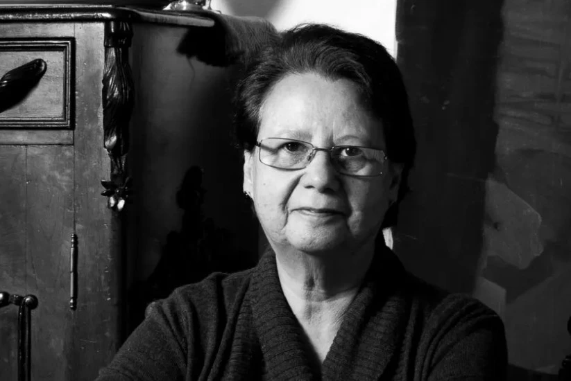 Retrato blanco y negro de Irene Vasco al lado de un mueble antiguo tallado