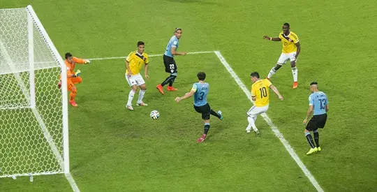 Jugador de Uruguay patea el balón frente a jugadores de Colombia.