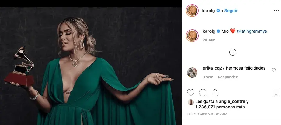 Karol G posando con un Grammy vestida de verde esmeralda