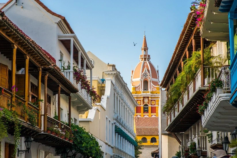 Vista de las Calle 4 en Cartagena, con balcones adornados de flores bajo un cielo azul despejado