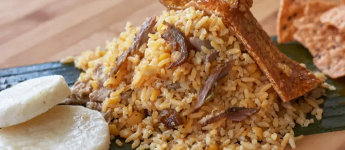 Plato de lechona colombiana, que consiste en arroz y guisantes, trozos de carne y una porción de piel de cerdo crujiente