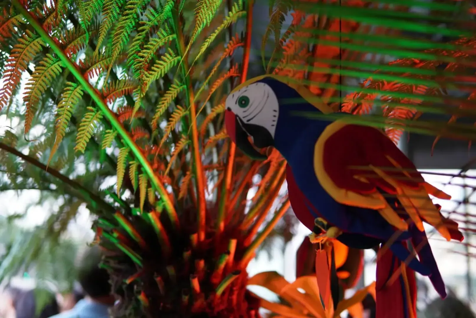 Loro decorativo entre hojas iluminadas con luces de colores
