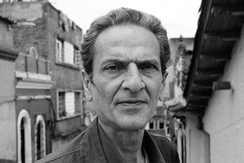 Retrato de Luis Fayad vistiendo en medio de un barrio con diferentes casas