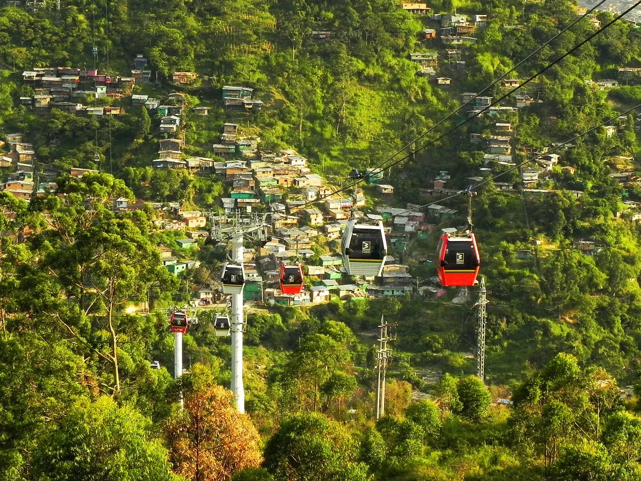 imágen de Metro Cable de Medellin en donde se ven arboles y casas de fondo, la ciudad de la eterna primavera, Medellin Colombia, turismo Colombia