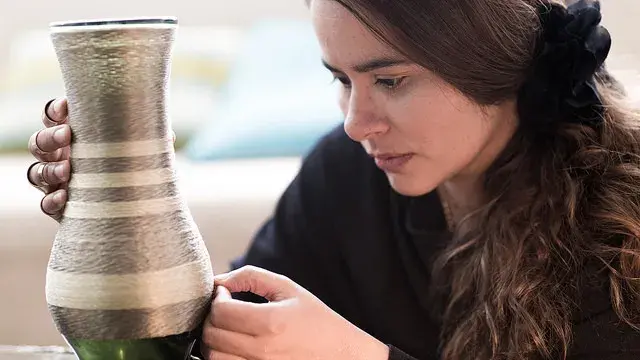 Mujer inspeccionando una artesanía de cerámica.