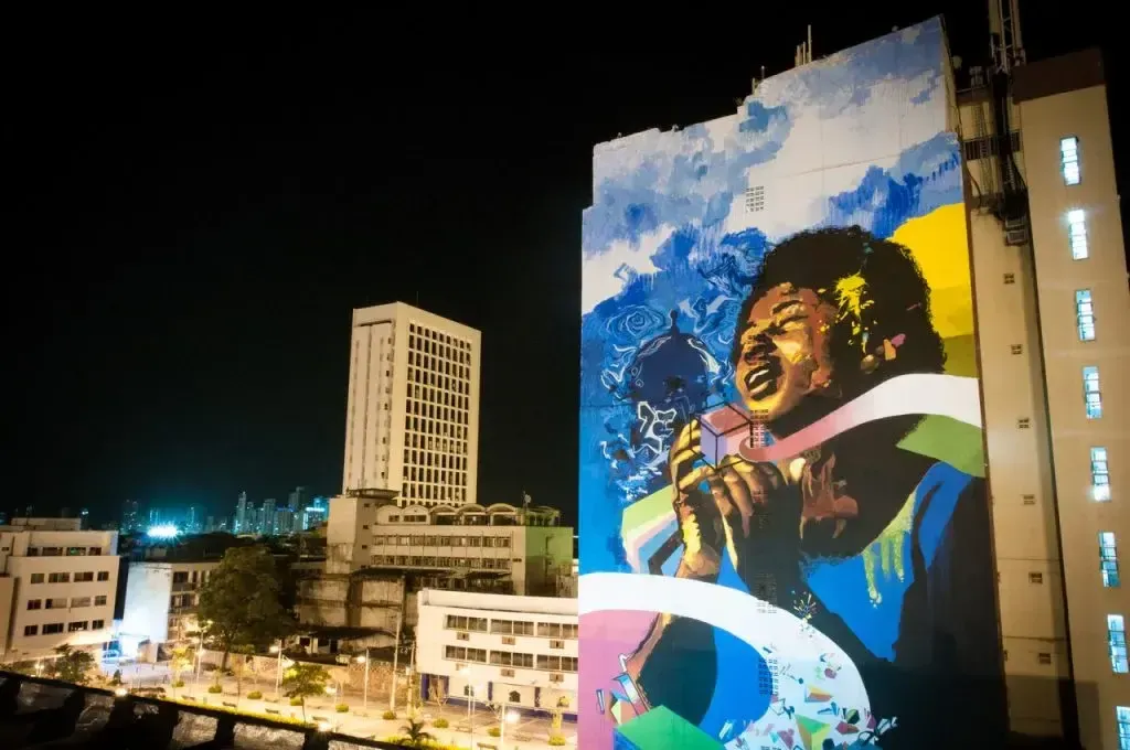 Mural iluminado de noche en fachada de edificio alto