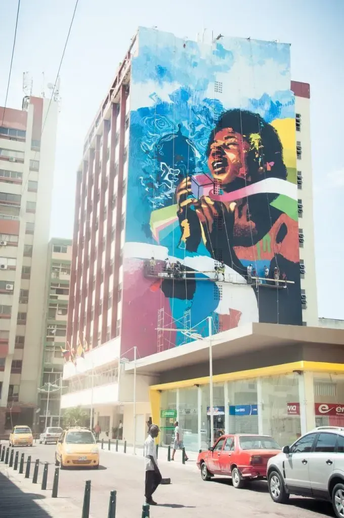 Artistas pintando mural colorido en edificio alto