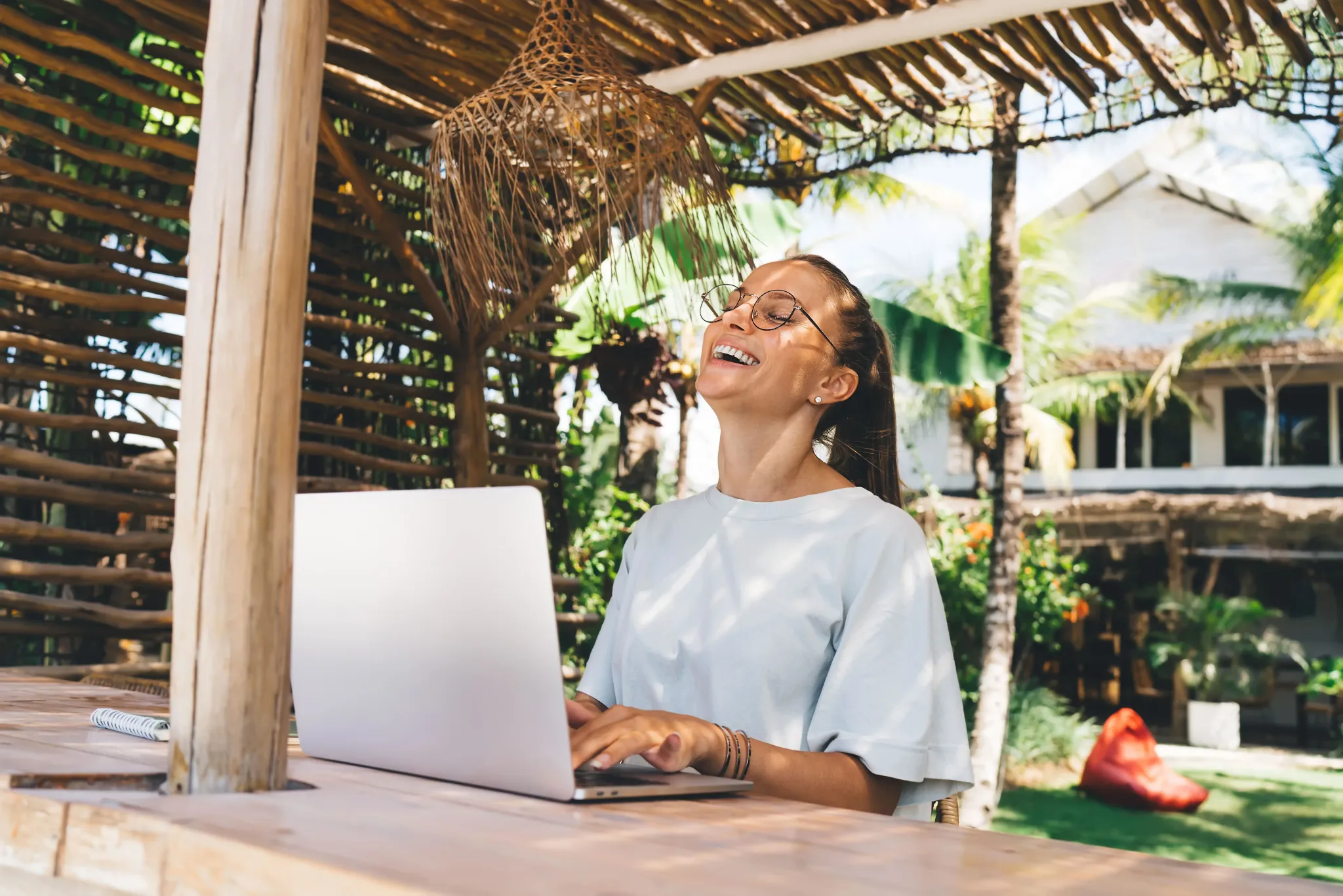 Mujer trabajando en su portátil desde una terraza tropical