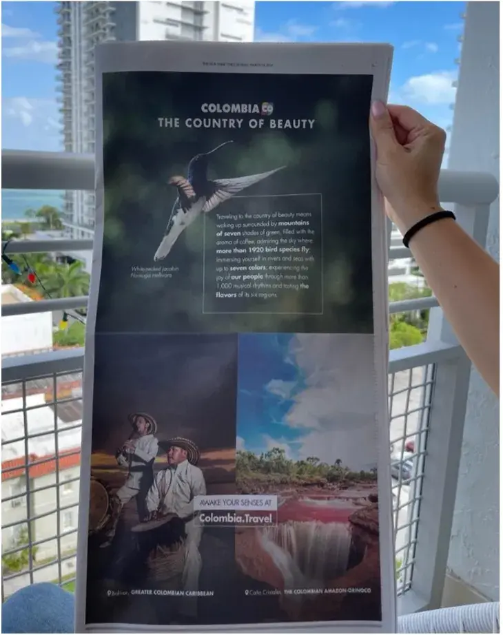 Manos sostienen un anuncio de Colombia: The Country of Beauty.