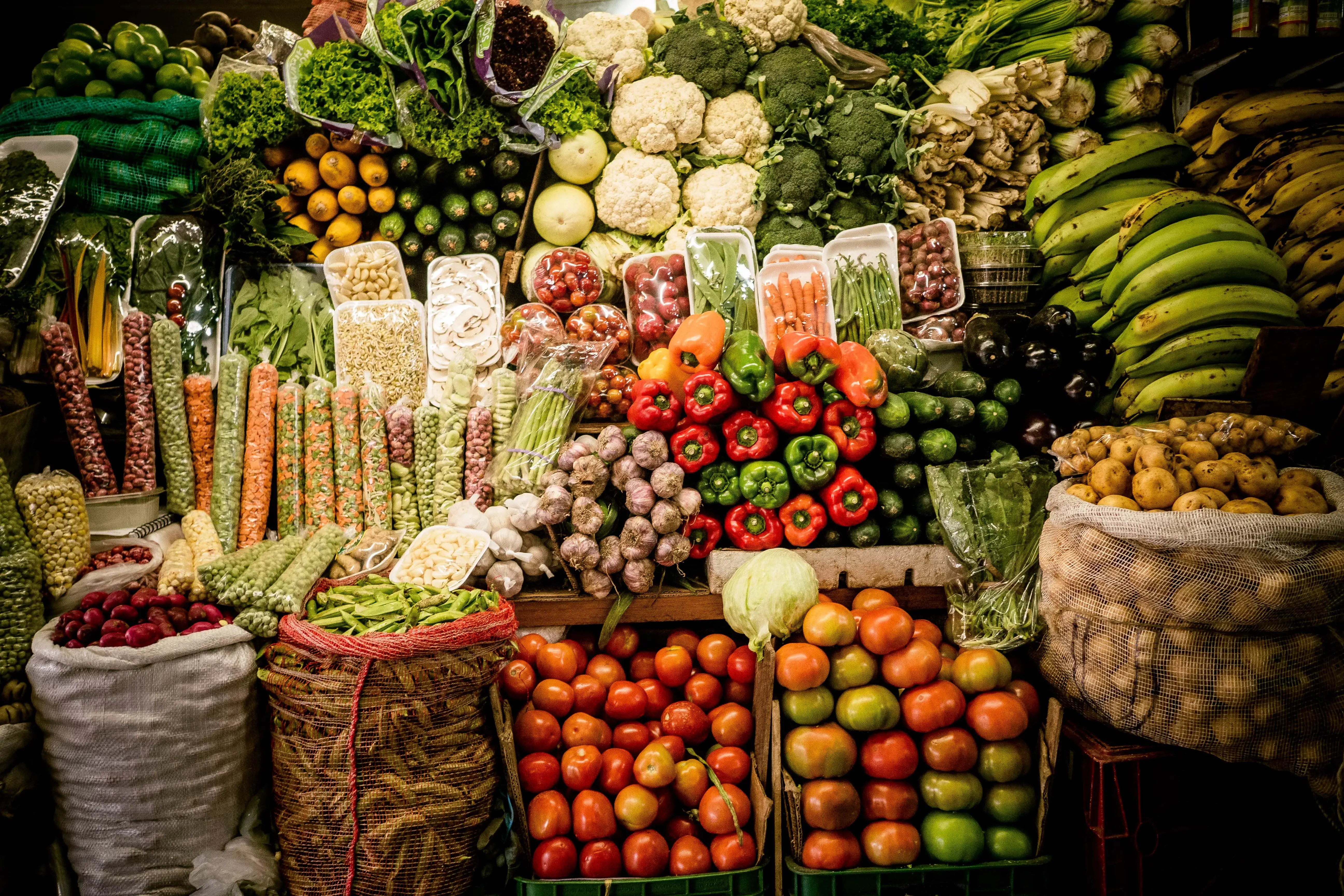 Puesto de mercado lleno de una gran variedad de verduras y frutas frescas con colores vivos.
