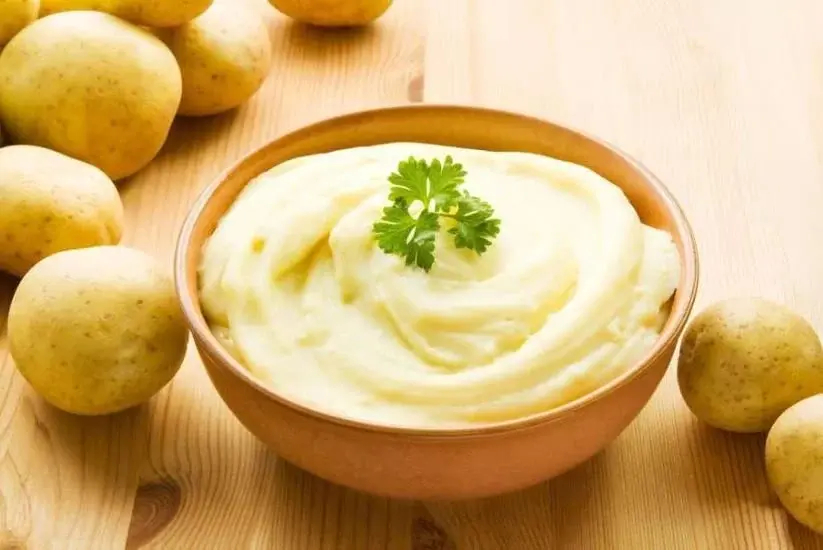 Puré de papa cremoso servido en un tazón con decoración de perejil
