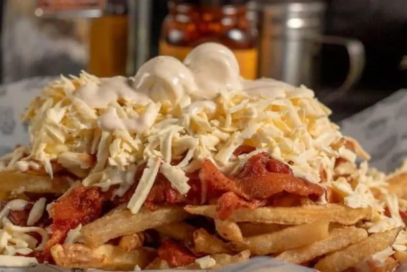 Salchipapas con salsa, queso rallado y papas fritas crujientes