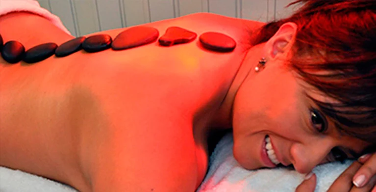 Mujer recibiendo terapia de piedras calientes en un spa