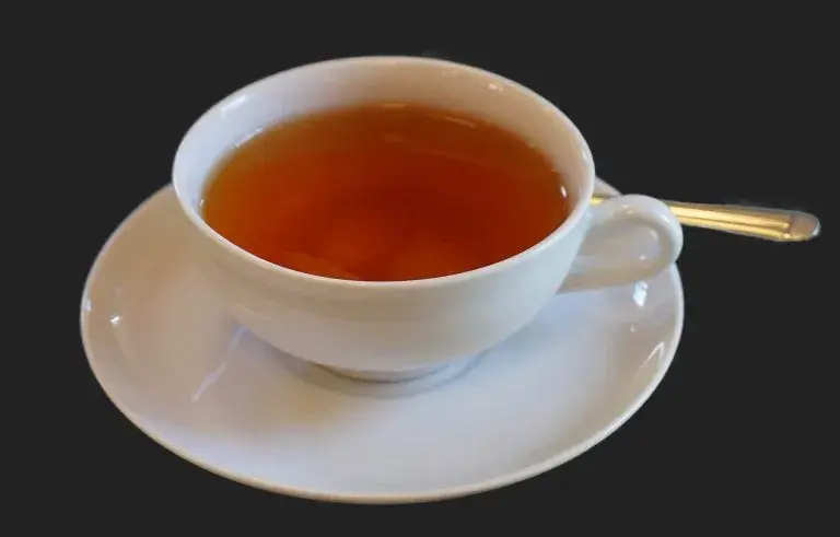 taza de Aguapanela sobre plato que se encuentra encima de una mesa negra, aguapanela, pisca, dulce típico, remedios caseros