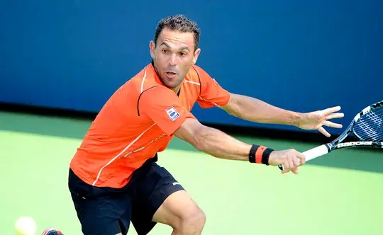 Tenista Víctor Estrella Burgos con camiseta naranja, golpeando la pelota de derecha en la cancha.