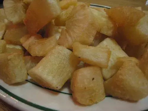 Portion of fried yucca served on a white plate.