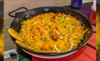 Arroz típico de la Costa Caribe de Colombia, servido en un sartén con vegetales y plátano frito