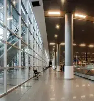 Pasillo moderno de aeropuerto con grandes ventanales y banda de equipaje.