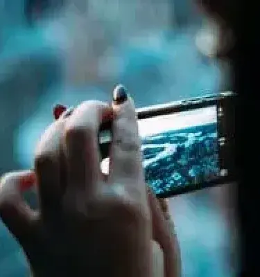 Mano de una mujer tomando una foto de un paisaje urbano con un celular.