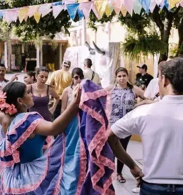 Parejas bailan en la calle decorada con banderines en un evento cultural