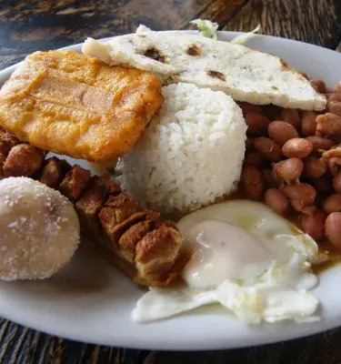 Bandeja paisa con sus once ingredientes sobre una mesa de madera.