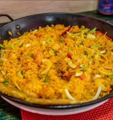 Arroz típico de la Costa Caribe de Colombia, servido en un sartén con vegetales y plátano frito