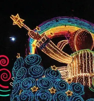 Figura iluminada con forma de niño y arcoíris en desfile nocturno
