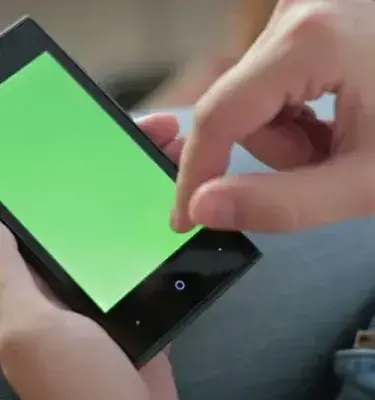 Persona usando un smartphone con pantalla verde sosteniéndolo con ambas manos